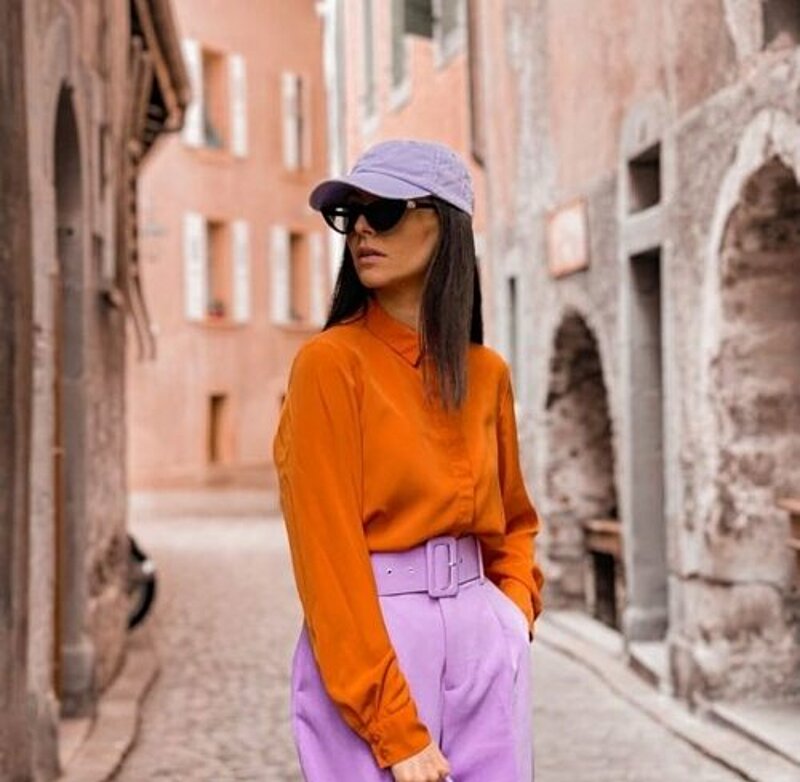 A woman in an orange shirt and purple pants.