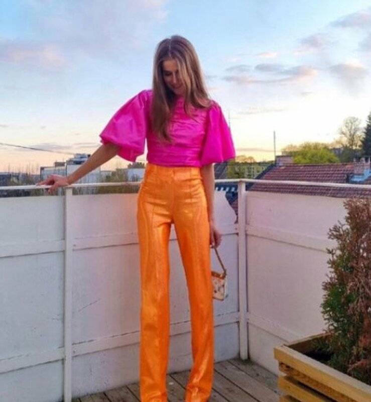 A woman wearing bright orange pants and a pink top.