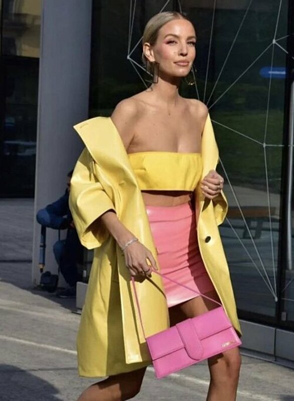 Woman in yellow top and pink skirt walking on street.