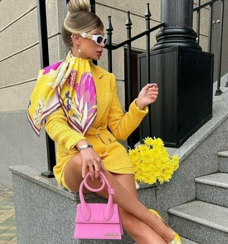 Woman in yellow suit and sunglasses sitting on steps.