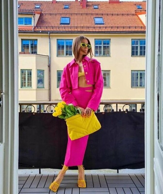 Woman in pink jacket and skirt on balcony.
