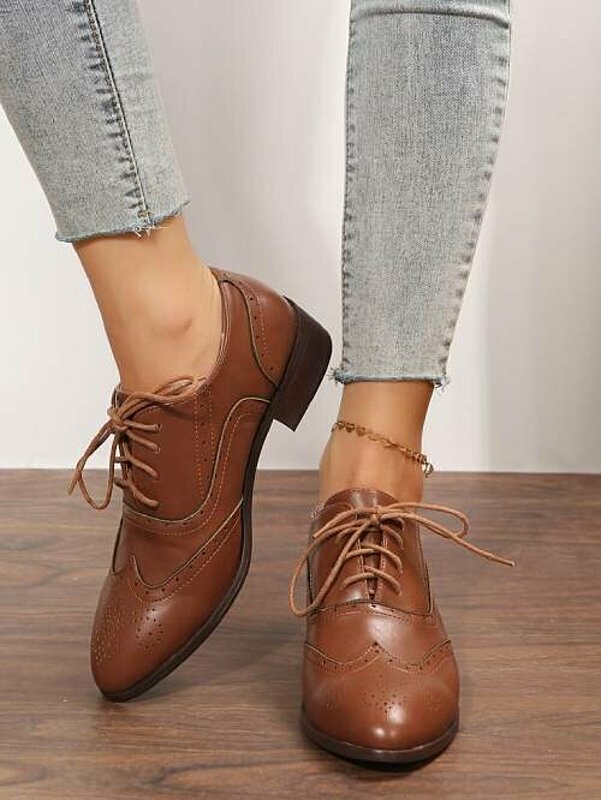 Woman's legs in brown leather shoes.