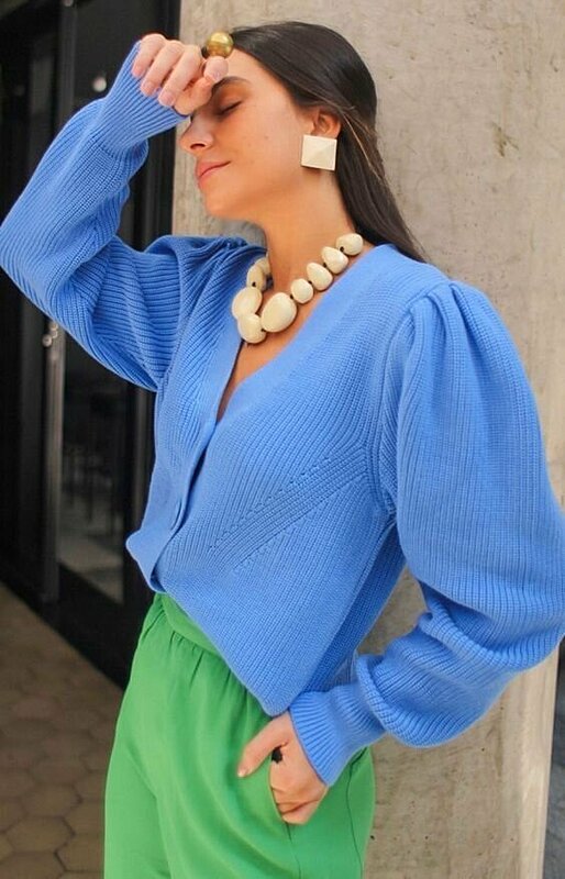 Stylish lady wearing blue top and green pants.